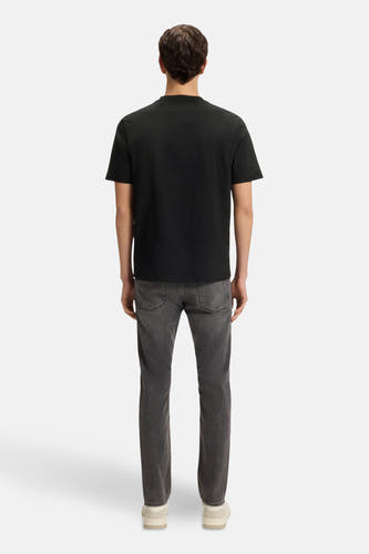 T-shirt noir à manches courtes de HUGO BOSS ORANGE, avec des jeans gris et des baskets blanches.