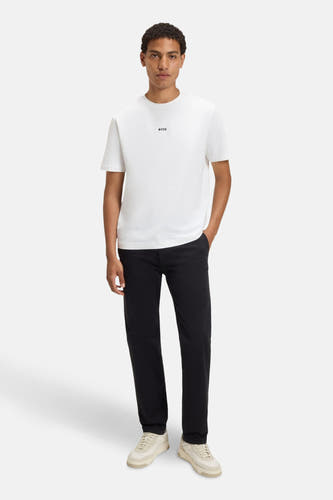 Wit T-shirt met korte mouwen van BOSS, gedragen met zwarte broek en crèmekleurige sneakers.