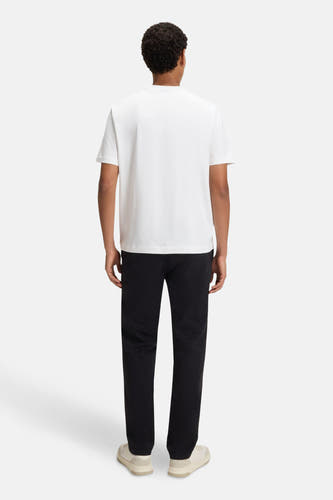 T-shirt blanc à manches courtes de HUGO BOSS ORANGE, vu de l'arrière, associé à un pantalon noir et des chaussures crème.