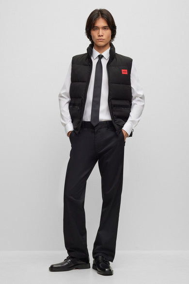 Man met zwarte bodywarmer, overhemd, stropdas en pantalon.