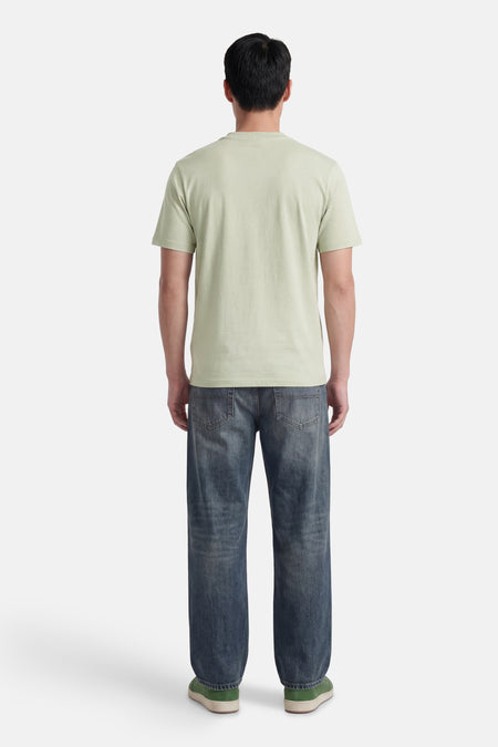 T-shirt vert à manches courtes de HUGO, dos d'un homme avec un jean foncé et des baskets vertes.