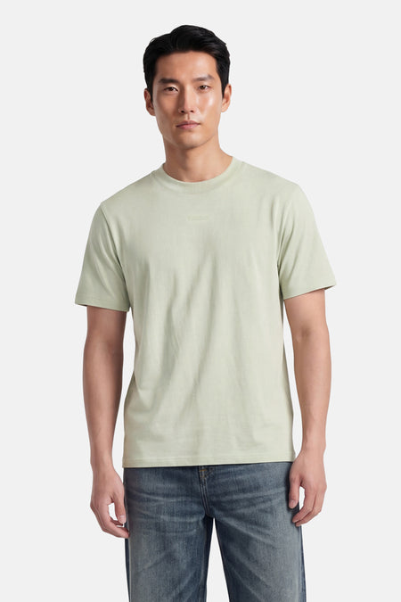 T-shirt vert à manches courtes de HUGO, avec logo discret sur la poitrine, porté par un homme en jean.