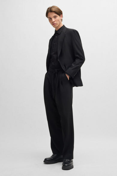 Chemise noire à manches longues de HUGO, portée avec un blazer et un pantalon large.