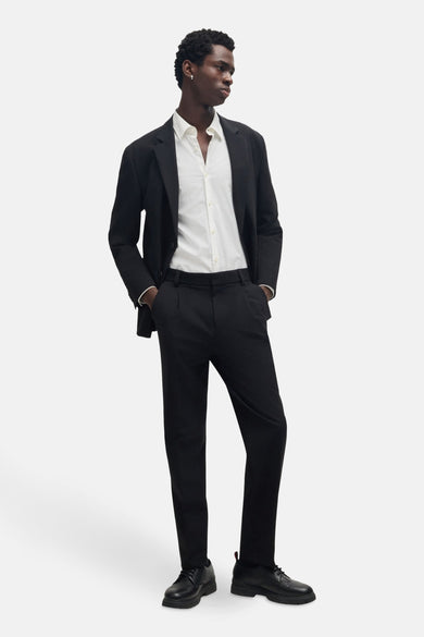 Chemise blanche à manches longues de HUGO, portée avec un blazer noir et un pantalon.