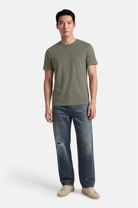 Kaki T-shirt met korte mouwen van HUGO BOSS ORANGE, gedragen met spijkerbroek en sneakers.