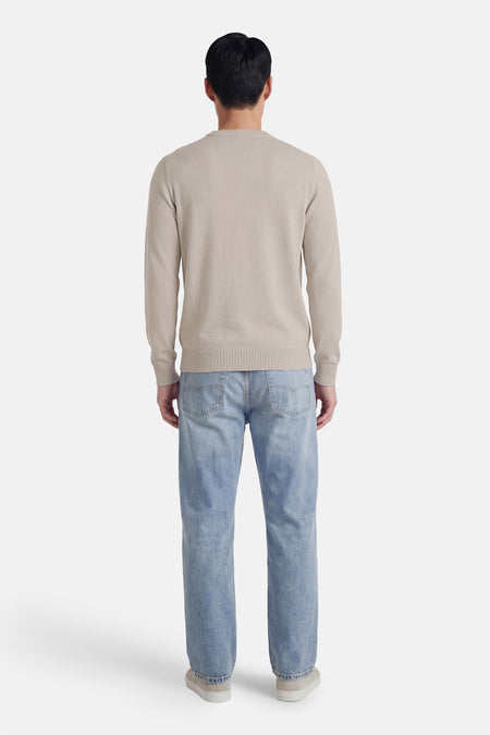 Pull gris à col rond de HUGO BOSS ORANGE, vu de dos, combiné avec un jean bleu et des chaussures claires.