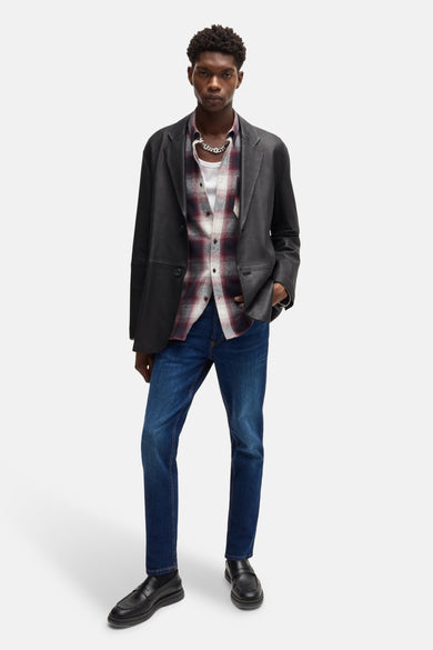 Jean tapered de denim bleu moyen HUGO, associé à une chemise à carreaux, un manteau noir et des chaussures noires.