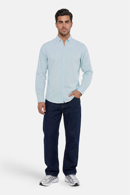 Chemise bleue à manches longues HUGO BOSS ORANGE avec col boutonné, portée avec un jean foncé et des baskets.
