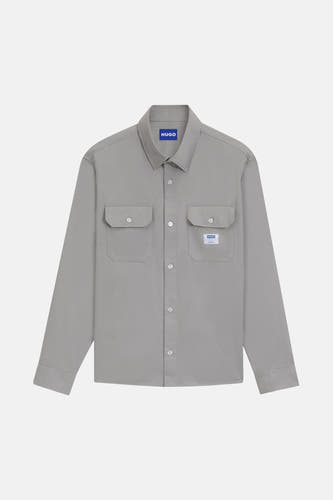 Chemise grise à manches longues de HUGO BLUE, avec deux poches po poitrine et col boutonné, sur un fond blanc.