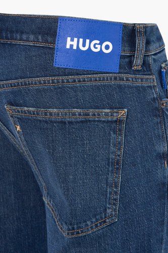 Close-up blauwe spijkerbroek met HUGO-logo.