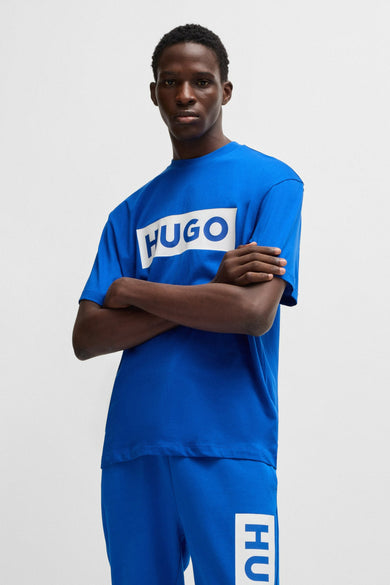T-shirt bleu à manches courtes de HUGO BLUE, porté avec un short de jogging bleu et des baskets blanches.