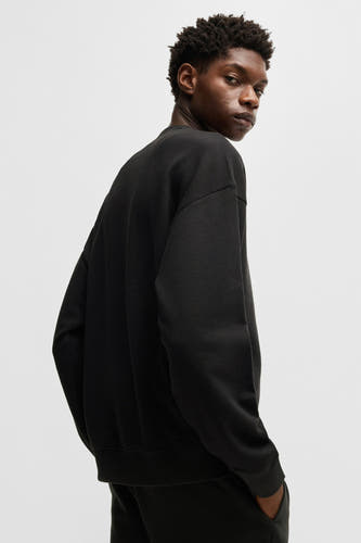 Pull-over noir avec col rond de HUGO, vu de l'arrière, avec un pantalon foncé.