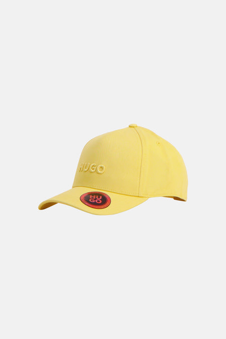 Casquette jaune de HUGO, avec un logo brodé sur le côté et un patch rond sur la visière.