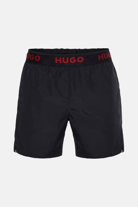 Maillot de bain noir HUGO, avec une ceinture élastique noire et des lettres 'HUGO' rouges.