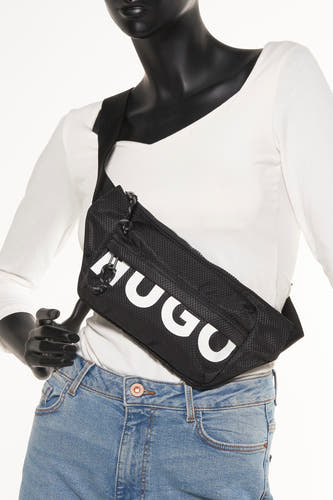 Sac à dos noir HUGO avec une texture et un logo HUGO blanc, porté avec un t-shirt blanc et un jean bleu.