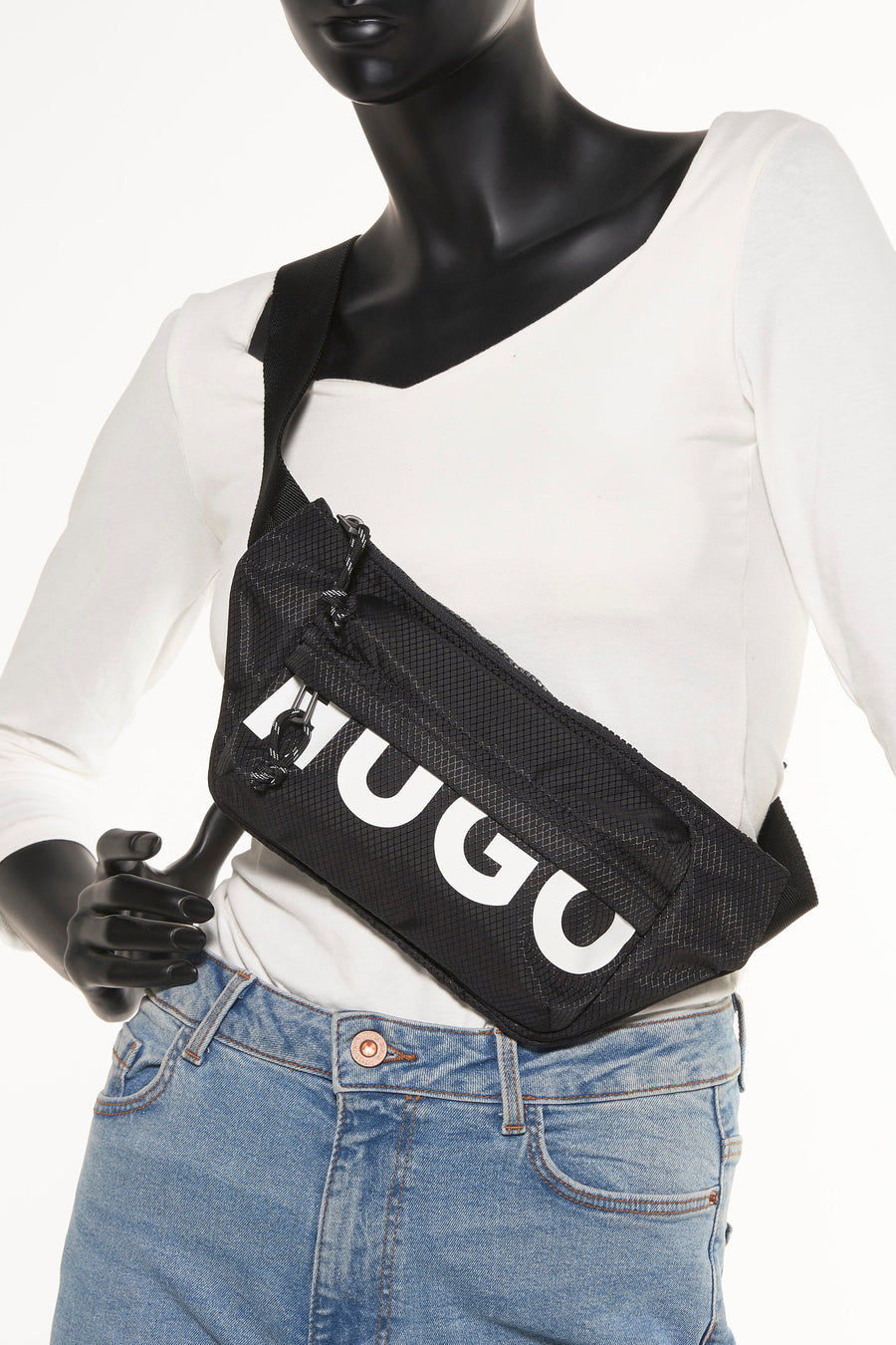 Sac à dos noir HUGO avec une texture et un logo HUGO blanc, porté avec un t-shirt blanc et un jean bleu.