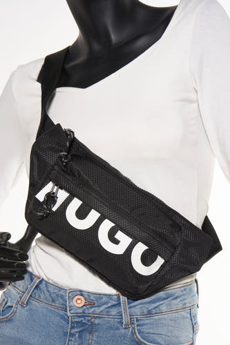 Sac à dos noir HUGO, avec un motif de carreaux et des lettres de marque blanches, porté sur une chemise blanche et un jean.