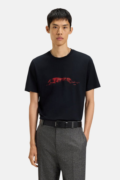T-shirt noir à manches courtes de HUGO, avec imprimé de chien rouge sur l'avant, associé à un pantalon gris et une ceinture.