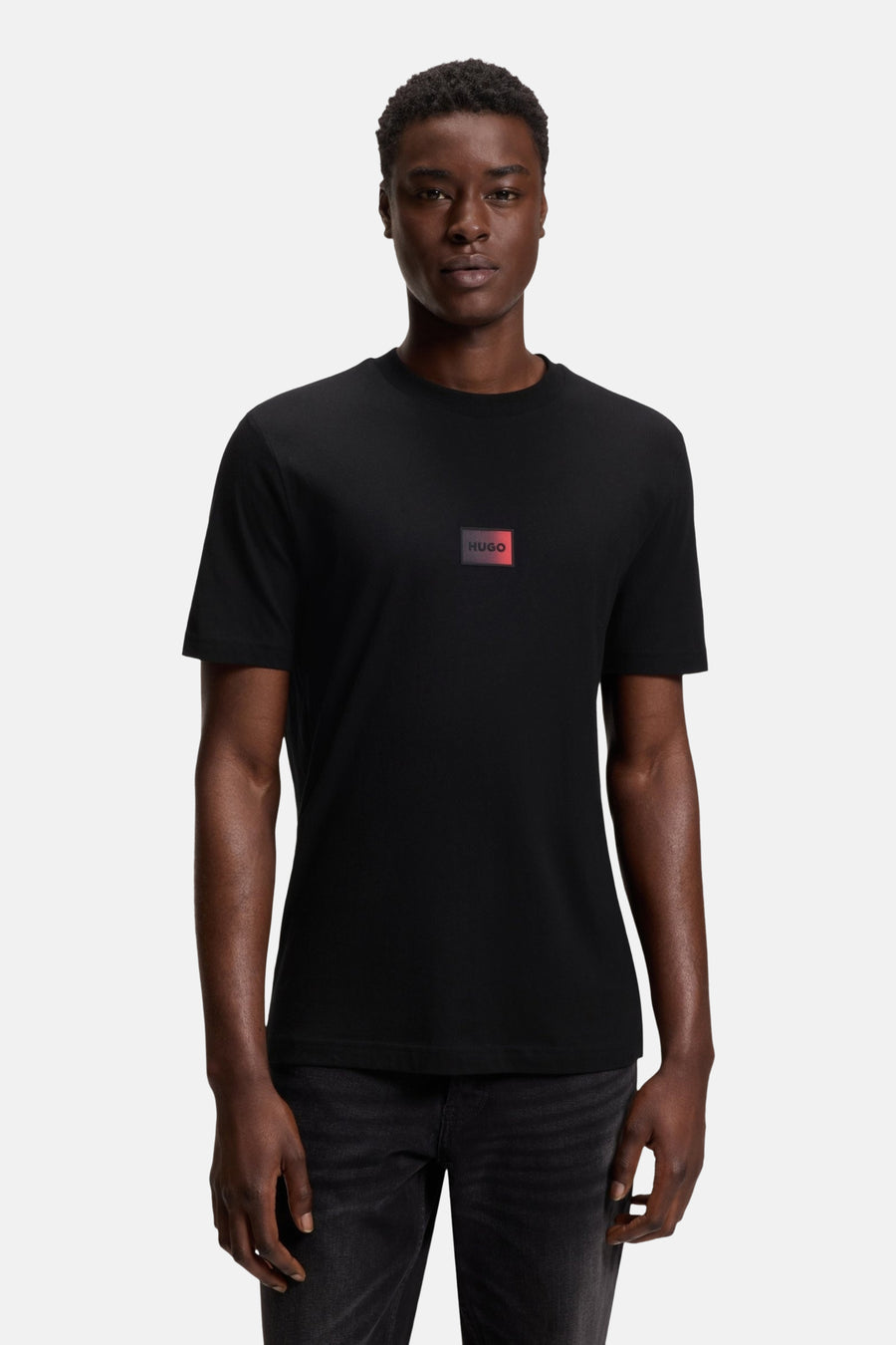 T-shirt noir à manches courtes de HUGO, avec un petit logo rouge sur la devanture.