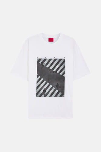 T-shirt blanc à manches courtes de HUGO, avec une impression d'un zébrée avec des personnes dessus et les lettres "HUGO".