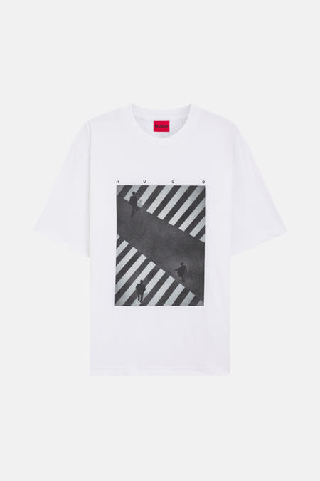 T-shirt blanc à manches courtes de HUGO, avec une impression d'un zébrée avec des personnes dessus et les lettres "HUGO".