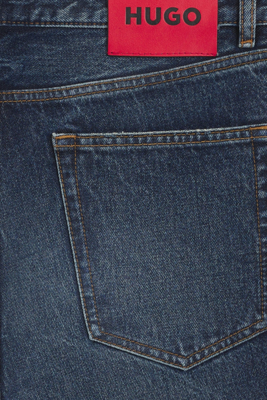 Jean droit en denim bleu foncé de HUGO, avec poche arrière et étiquette rouge de la marque.