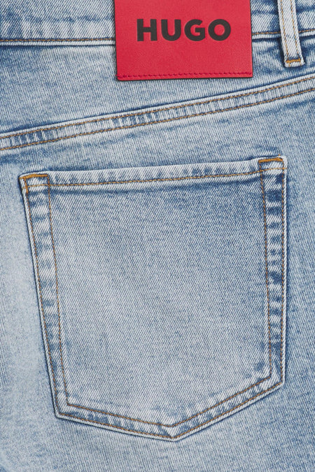 Lichtblauwe jeansshort van spijkerstof van HUGO, met een opgestikte achterzak en een rode HUGO-merkpatch bovenaan.