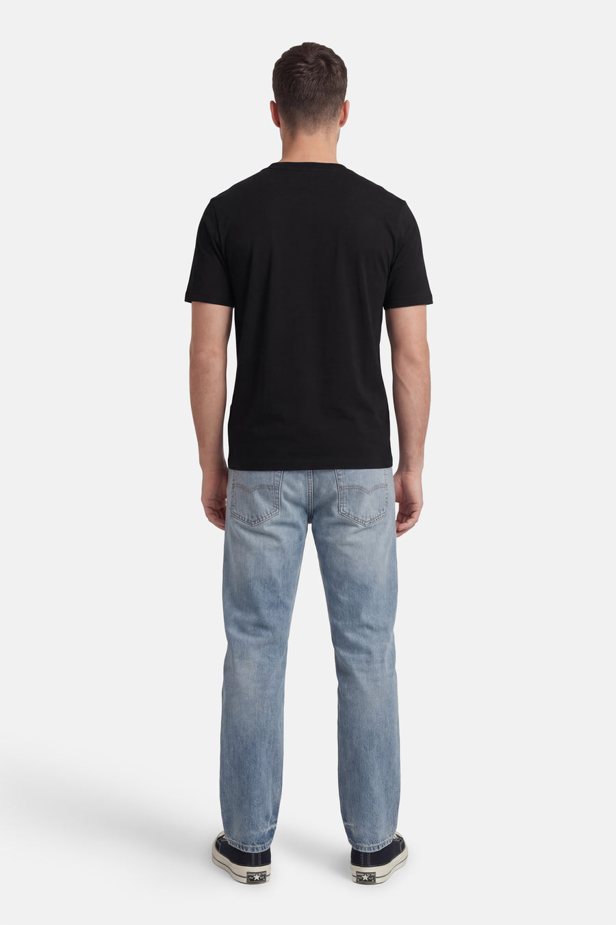 T-shirt noir à manches courtes de HUGO, vu de dos, associé à un jean bleu et des baskets foncées.