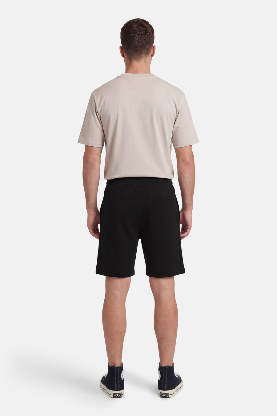 Short noir de HUGO, vu de dos, combiné avec un t-shirt beige et des baskets montantes.