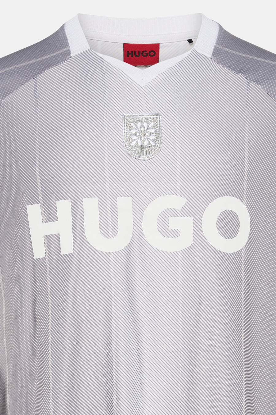 T-shirt à rayures gris clair et blanc de HUGO avec col en V, écusson brodé et grandes lettres blanches de la marque sur la poitrine.
