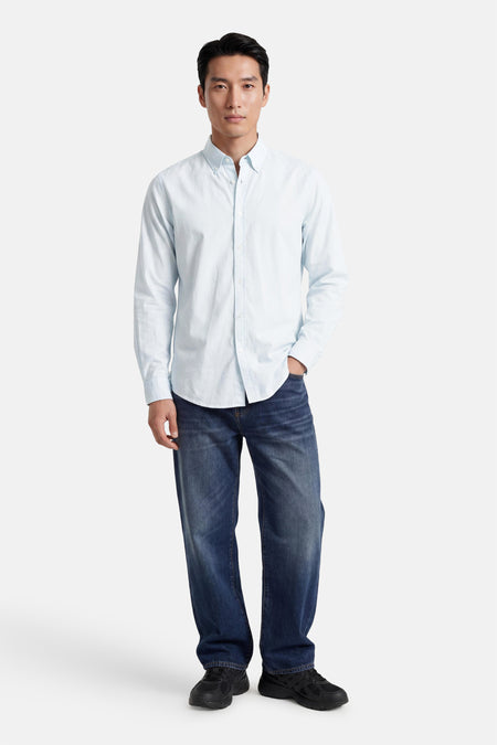 Chemise turquoise de HUGO BOSS ORANGE, portée par un homme avec un jean bleu foncé et des baskets noires.