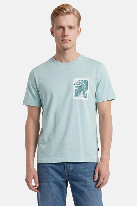 Turquoise T-shirt met korte mouwen van HUGO BOSS ORANGE met witte print van palmblad en '7.8' op de borst, gedragen door een man in jeans.