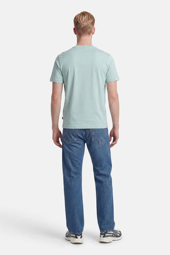 Turquoise T-shirt met korte mouwen van HUGO BOSS ORANGE, de achterkant gedragen door een man met blond haar, een blauwe spijkerbroek en sneakers.