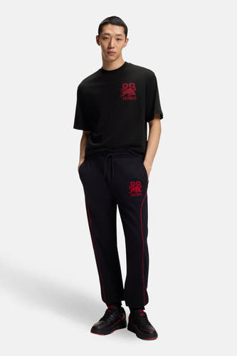 T-shirt noir à manches courtes de HUGO, avec un imprimé rouge sur la poitrine.