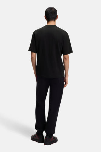 T-shirt noir à manches courtes de HUGO, vu de dos, associé à un pantalon de survêtement foncé.