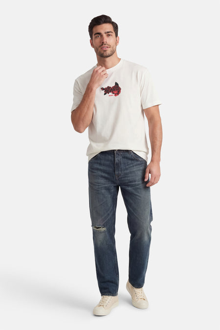Wit T-shirt met korte mouwen van HUGO, met een roosmotief op de borst, gecombineerd met donkerblauwe jeans met scheuren en crèmekleurige sneakers.