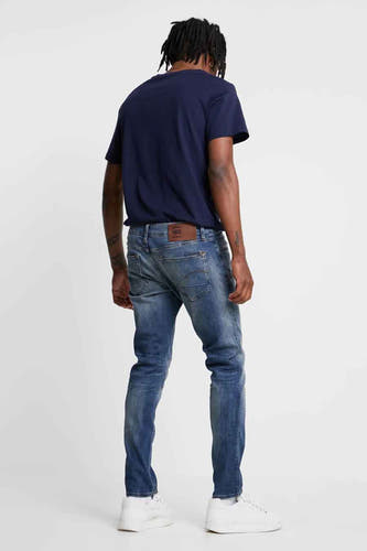 Jean slim en denim bleu moyen de G-Star RAW, vu de derrière, avec des baskets blanches.