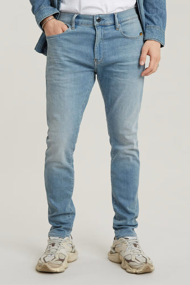 Jean skinny bleu clair de G-Star RAW, porté avec une veste en denim et des baskets blanches.