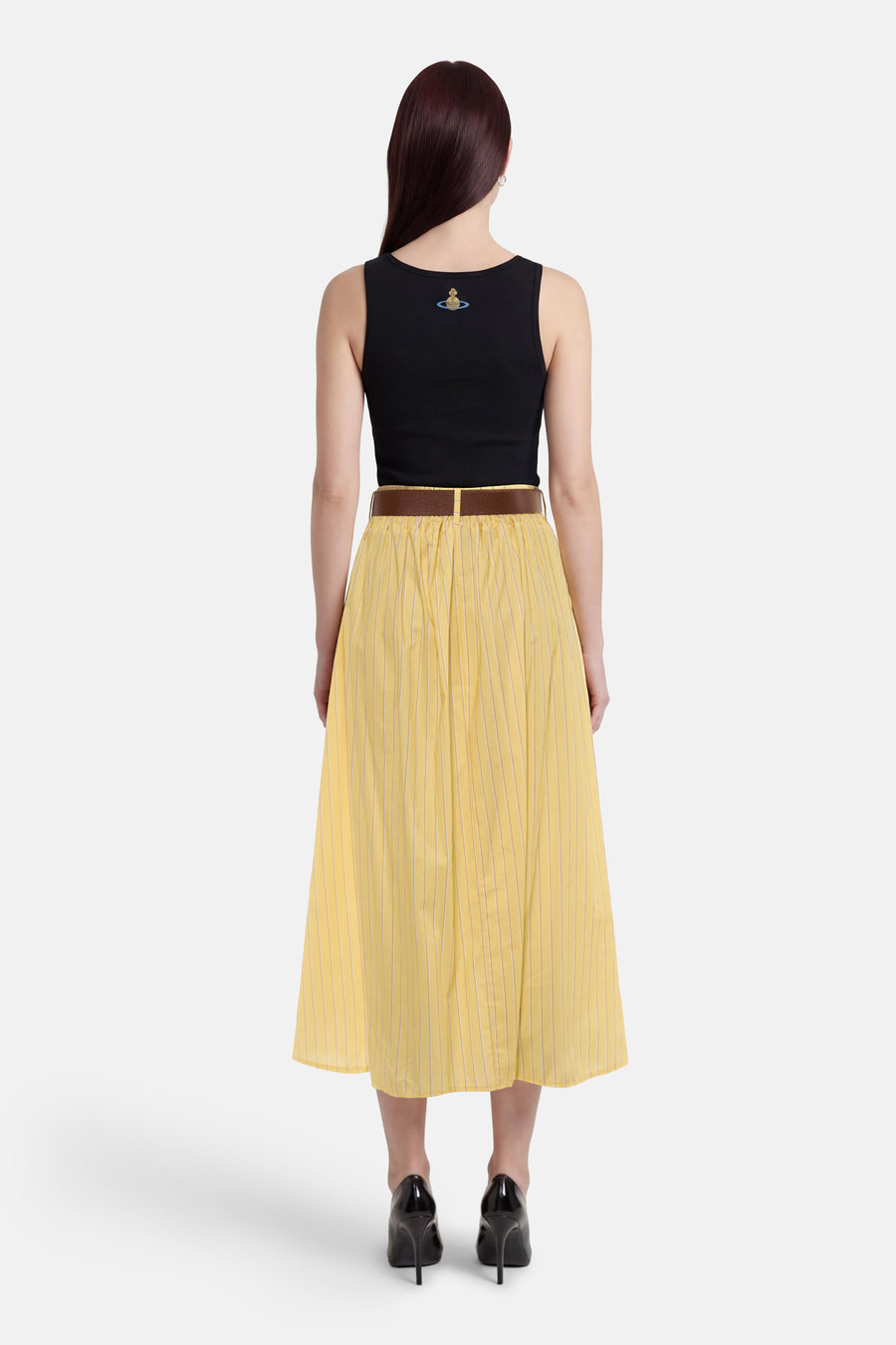 Jupe jaune de Terra di Siena avec de fines rayures verticales, combinée avec un haut noir et une ceinture marron.