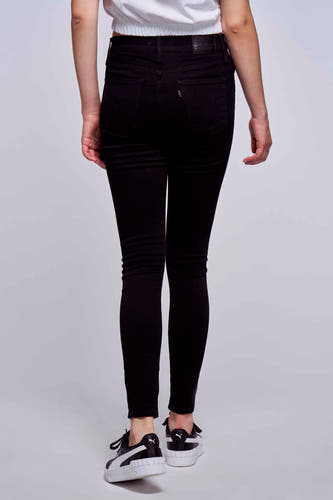 Zwarte skinny jeans van Levi's, achterkant gezien, gecombineerd met witte top en zwart-witte sneakers.