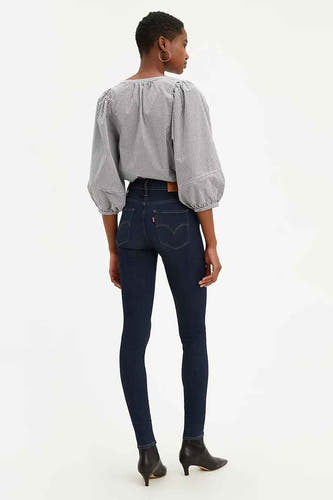 Jean skinny bleu marine de Levi's, avec une taille haute, associé à une blouse à manches longues et des escarpins noirs.