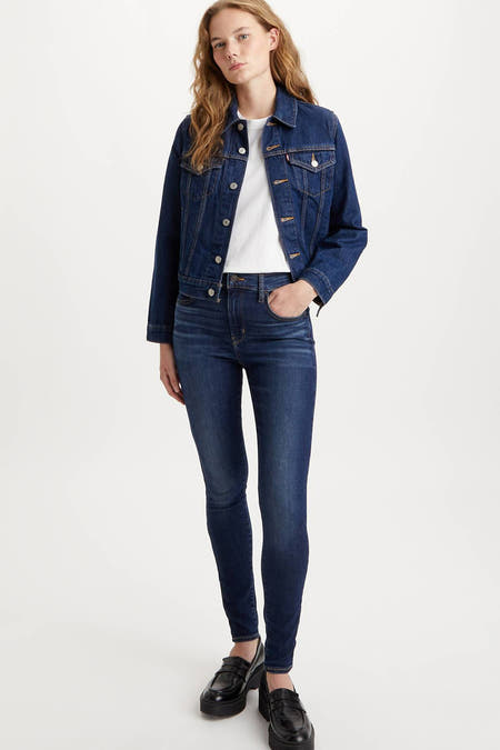 Jean skinny bleu marine de Levi's, avec des rivets caractéristiques sur la poche arrière et une étiquette en cuir sur la ceinture.
