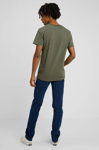 T-shirt vert de Levi's, vu de de derrière, avec des jeans bleu marine et des baskets blanches.