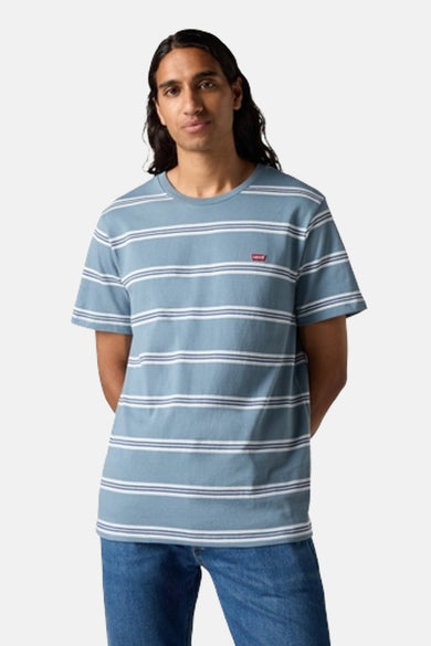 Een man die een blauw gestreept T-shirt en jeans draagt.