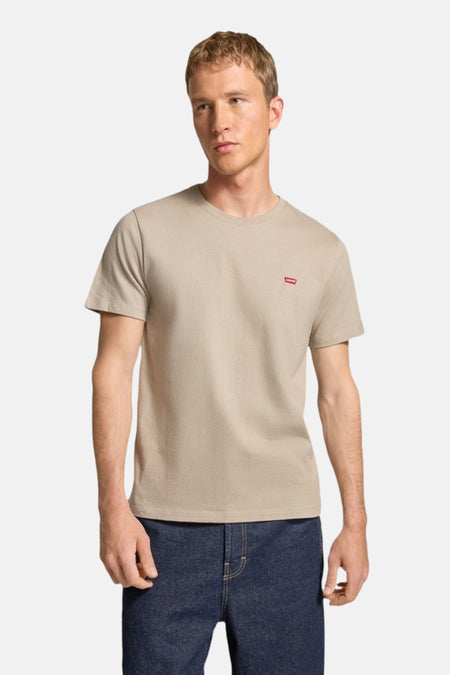 Man draagt beige Levi's T-shirt en donkere jeans.