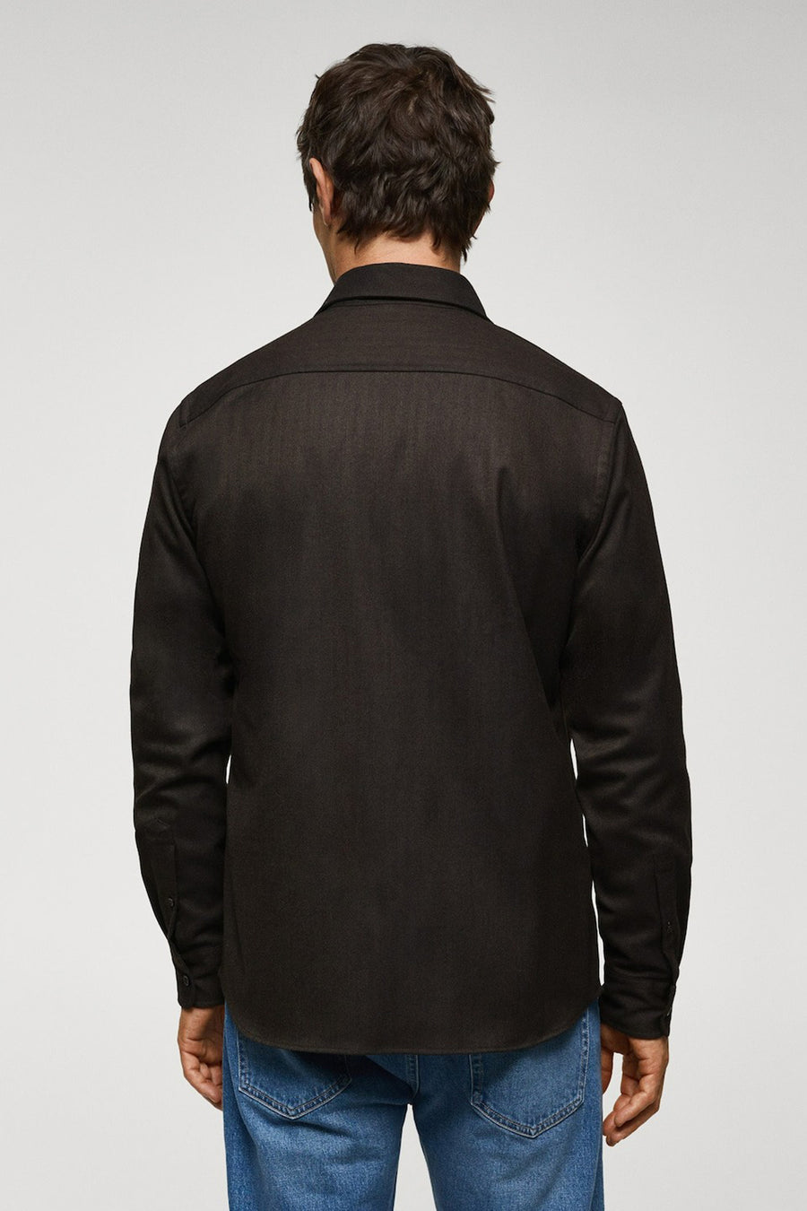 Chemise brune à manches longues de MANGO, vue de derrière, portée avec un jean bleu.