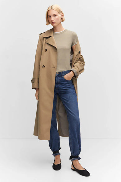 T-shirt vert à manches courtes de MANGO, porté sous un trench-coat beige, avec un jean bleu et des ballerines noires, vue de face.