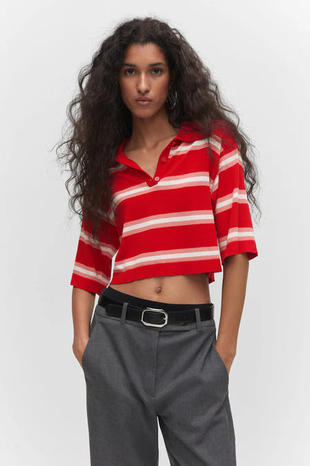 T-shirt rouge de MANGO avec des rayures blanches, porté avec une ceinture noire et un pantalon gris.