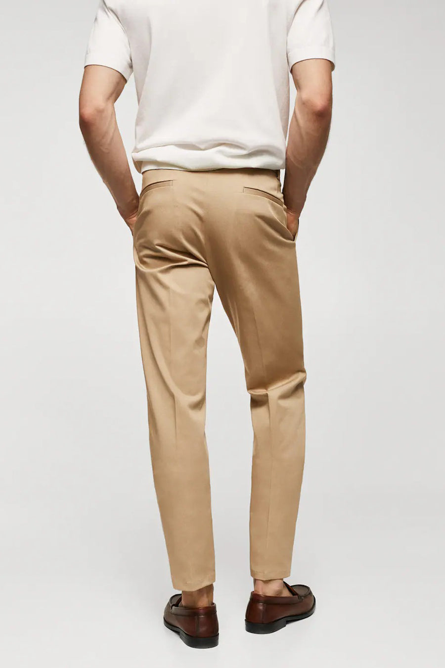 Pantalon chino marron de MANGO, vu de de derrière, associé à une chemise blanche et des mocassins marrons.