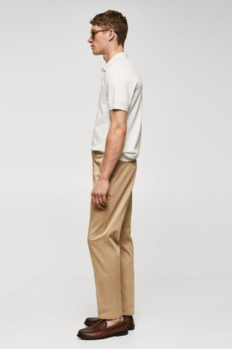 Pantalon chino marron de MANGO, vu de l'arrière, associé à un polo blanc et des loafers en cuir marron.